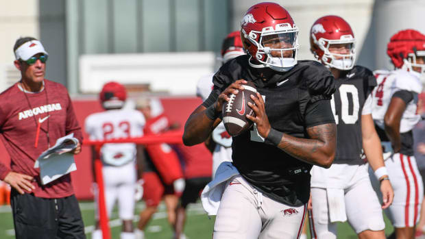 Razorbacks quarterback KJ Jefferson rolling out while Dan Enos looks on